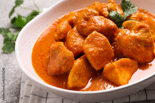 Bowl of delicious chicken curry on light grey table, closeup