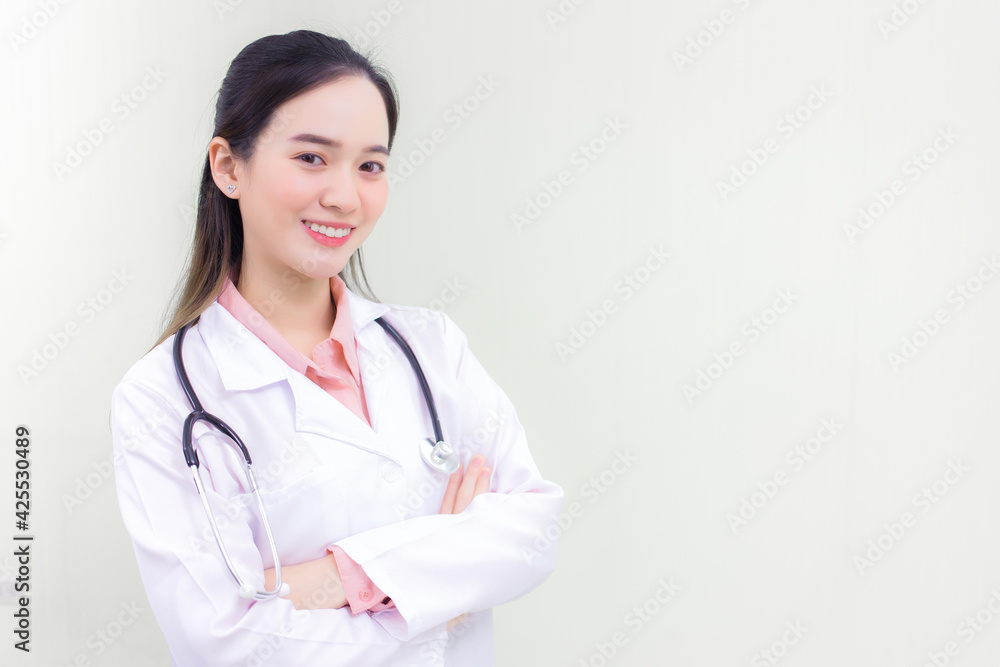 Young beautiful Asian woman doctor Standing with arms crossed happy and smile in hospital. Wearing a white robe and stethoscope Young beautiful Asian woman doctor Standing with arms crossed happy and smile in hospital. Wearing a white robe and stethoscope