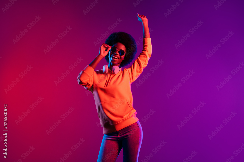 Photo of attractive cheerful dark skin person arm touch sunglass beaming smile isolated on bright background Photo of attractive cheerful dark skin person arm touch sunglass beaming smile isolated on bright background