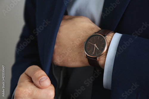 Businessman with luxury wrist watch on grey background, closeup