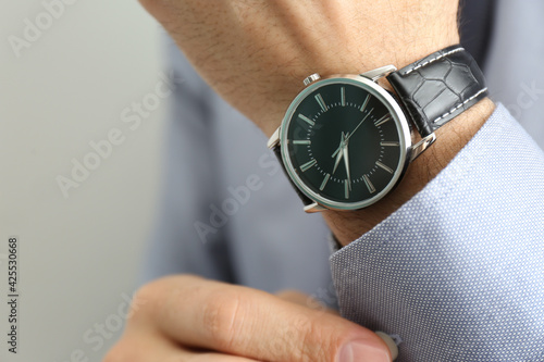 Man with luxury wrist watch on grey background, closeup. Space for text