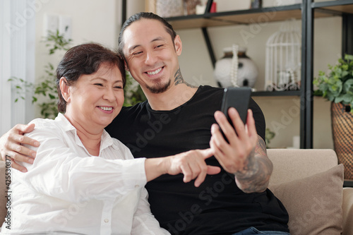Happy handsome mixed-race man asking mature mother to take selfie with him © DragonImages
