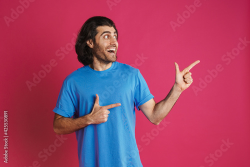 Excited brunette man pointing fingers aside and smiling photo