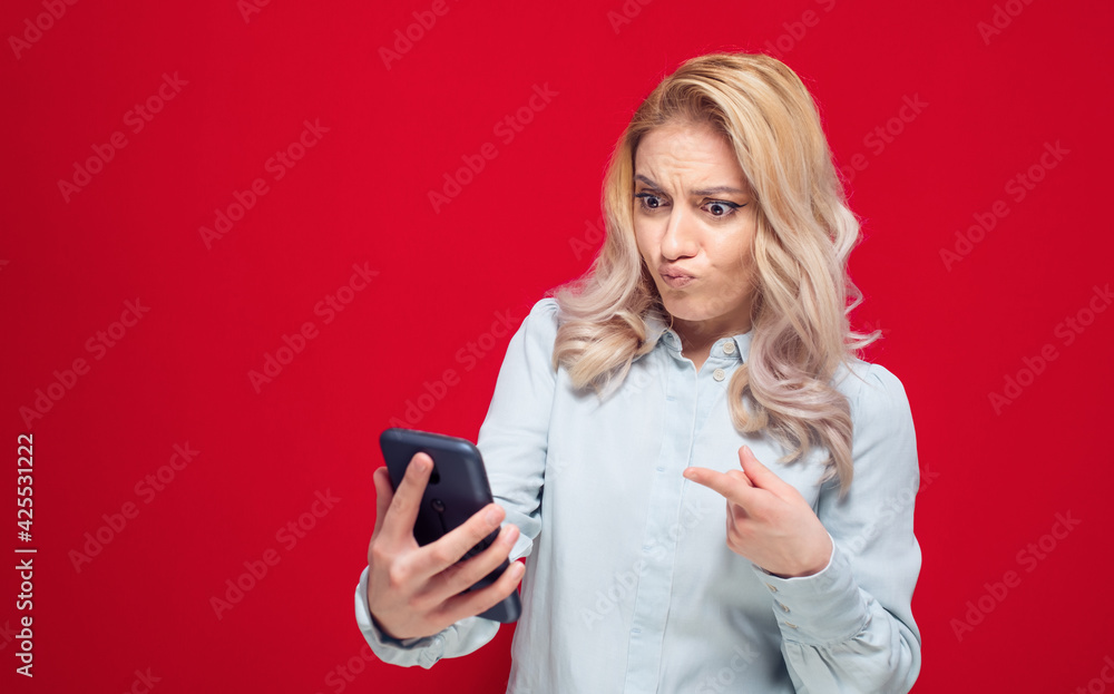 Funny angry woman holding the mobile phone while browsing and make a grimace, isolated on white background Funny angry woman holding the mobile phone while browsing and make a grimace, isolated on white background