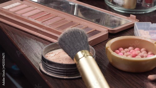 Female hand puts face powder box and brush on cosmetic table close up photo