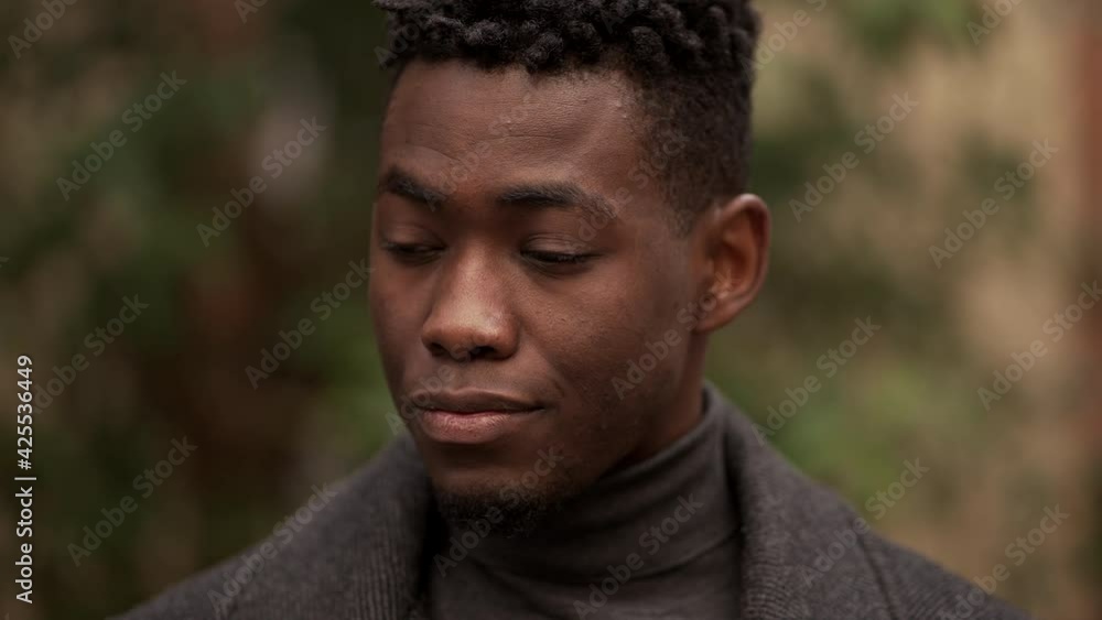 Handsome young black man standing outdoors thinking Handsome young black man standing outdoors thinking