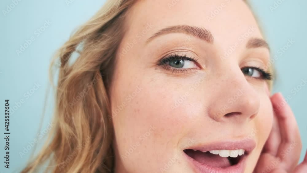 A beautiful woman is looking at her wrinkles standing isolated over blue wall in a studio A beautiful woman is looking at her wrinkles standing isolated over blue wall in a studio