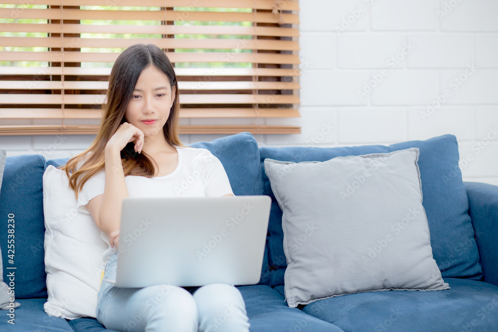 Young asian business woman smile and work from home with laptop computer online to internet on sofa in living room, freelance girl using notebook on couch with comfort, new normal, lifestyle concept. Young asian business woman smile and work from home with laptop computer online to internet on sofa in living room, freelance girl using notebook on couch with comfort, new normal, lifestyle concept.