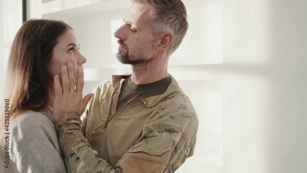 A soldier man is wiping tears from the face of his wife standing at home A soldier man is wiping tears from the face of his wife standing at home