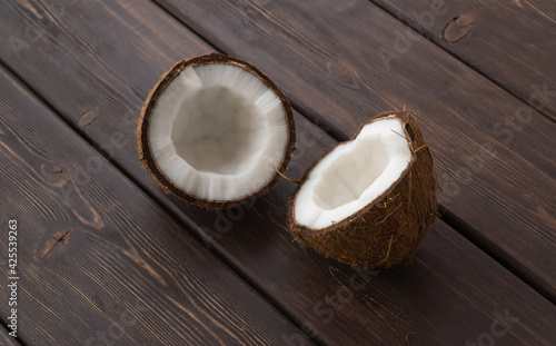 split coconut on wooden planks. Coco, ripe palm fruit. outside of the fruit is covered with a leathery exocarp. nut is useful, improves the condition of the body in many diseases. copy space