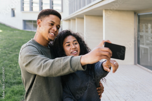 Latino couple using cell phone during a video call with friends and family. Bride and groom taking a selfie of an unforgettable moment.  © MANUEL