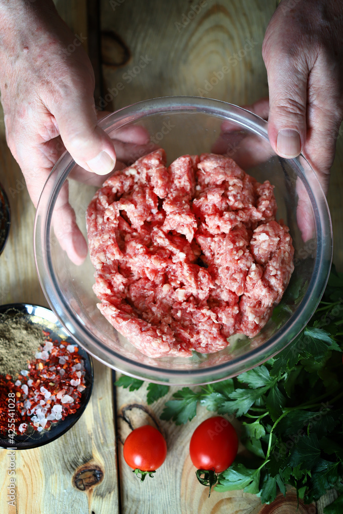 Minced meat in a bowl and the hands of the cook. Cooking minced meat for burgers or grilling. Minced meat in a bowl and the hands of the cook. Cooking minced meat for burgers or grilling.