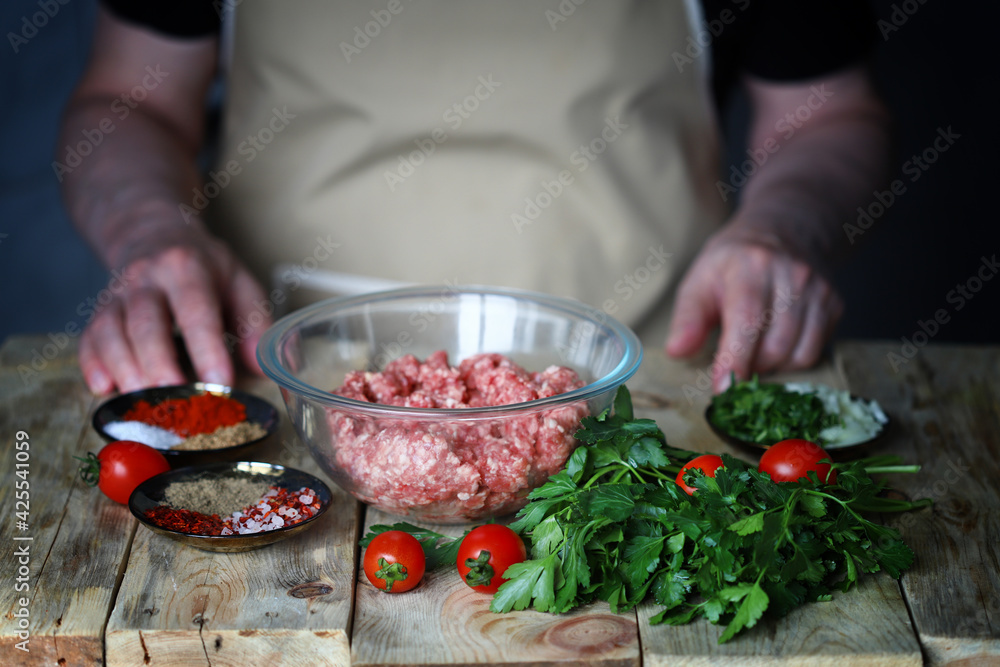 Minced meat in a bowl and the hands of the cook. Cooking minced meat for burgers or grilling.