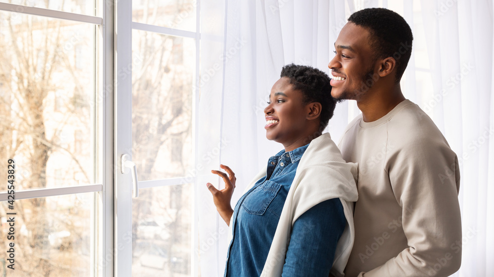Black couple standing near glass window indoors Black couple standing near glass window indoors