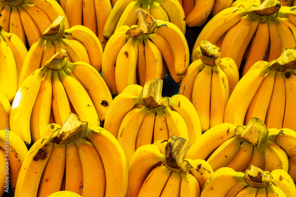 Bananas stacked on a market as a background.