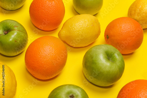 green apples, lemons and oranges on a yellow background close-up.  fruits, vitamins, proper healthy nutrition. Diet