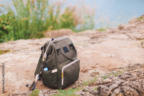 Hipster khaki backpack closeup Front view tourist traveler bag on footpath background . Backpack resting on the ground after hike. Hiking trips and travelling with rucksack concept. Copy space