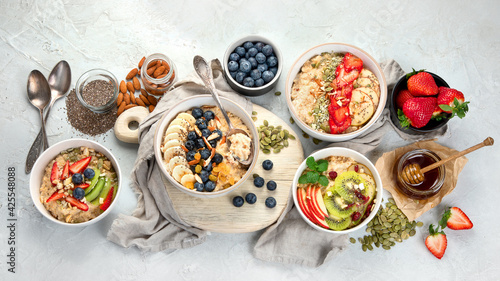 Oatmeal bowls with delicious fruits and fresh berries on light background.