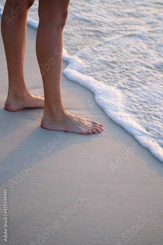 Female legs while walking on the beach by the water