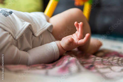 Hands and feet of a baby lying on a blanket. Baby's outstretched hand. Baby care.