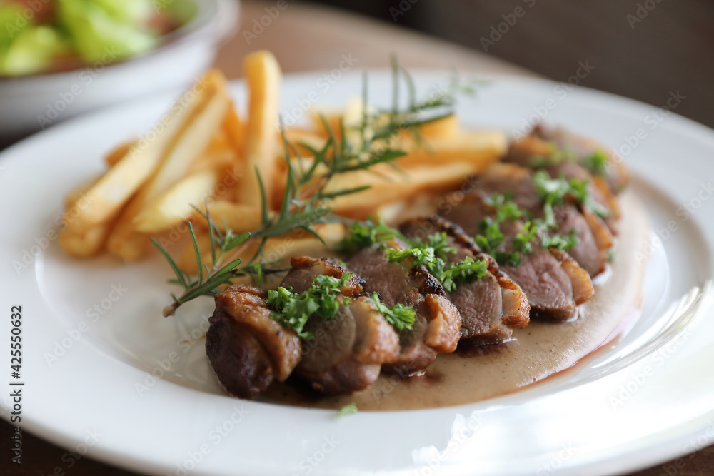 Duck magret confit with chips on wood table Duck magret confit with chips on wood table