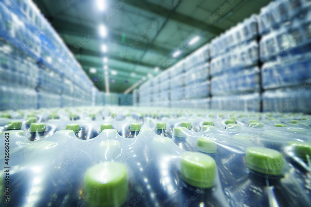 a huge industrial warehouse with plastic food wrap wrapped plastic bottles with carbonated drinks,  water or beer. - obrazy, fototapety, plakaty 