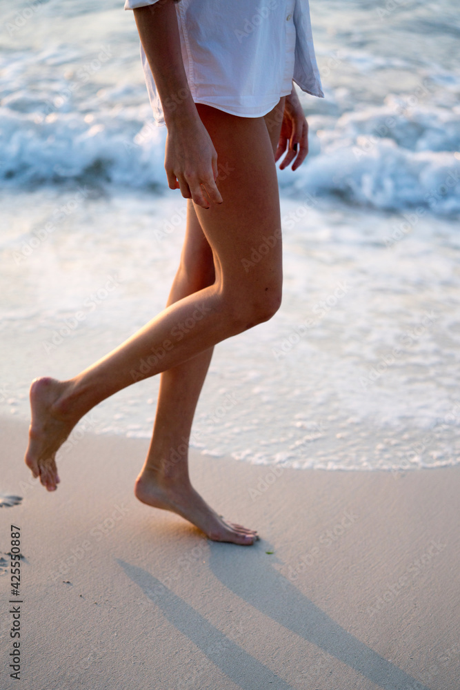 Female legs while walking on the beach by the water Female legs while walking on the beach by the water