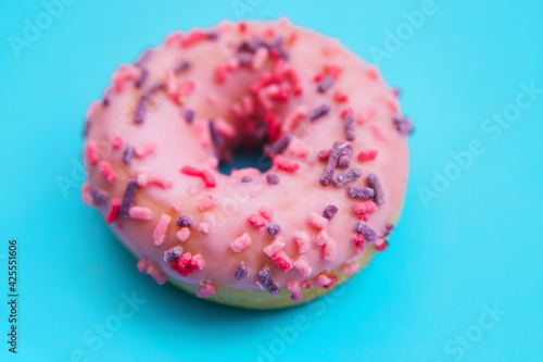 One pink donut on a blue background. Sweet snack.