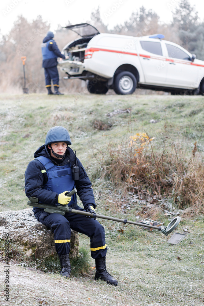 Men work in emergencies. Emergency workers work outdoors. A man in uniform works with a metal detector Men work in emergencies. Emergency workers work outdoors. A man in uniform works with a metal detector