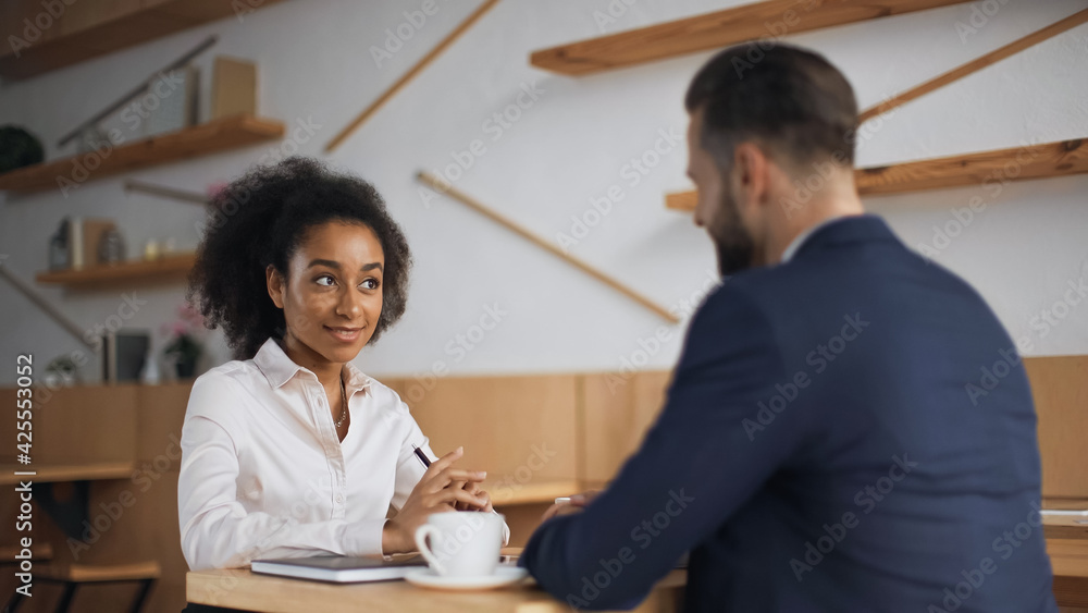 Fototapeta premium multiethnic business partners talking during meeting in cafe