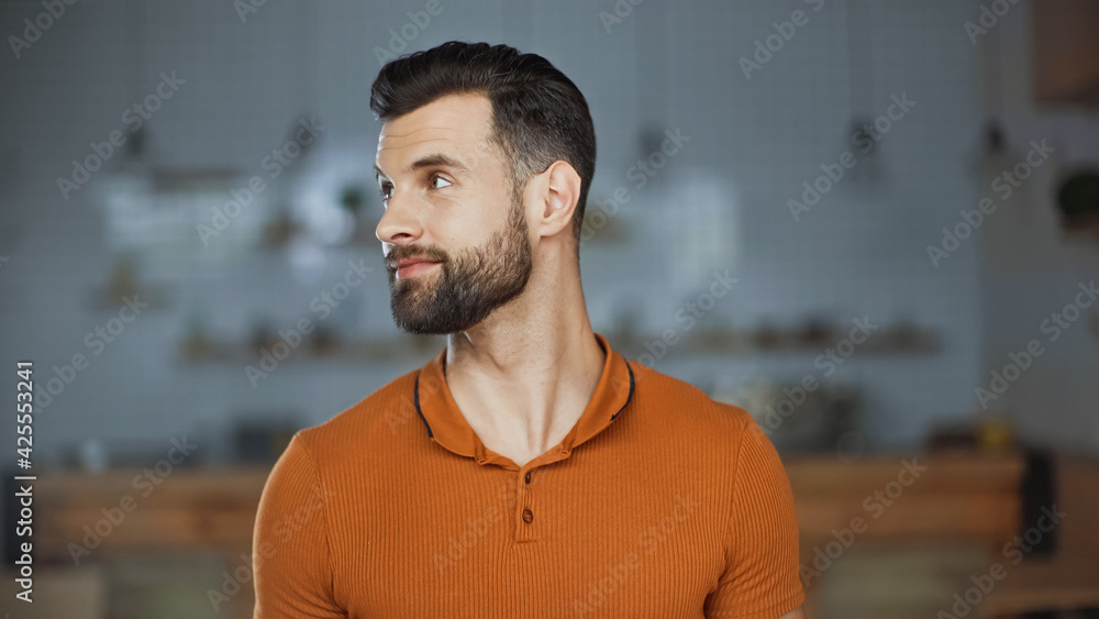 bearded man in orange t-shirt looking away in cafe bearded man in orange t-shirt looking away in cafe