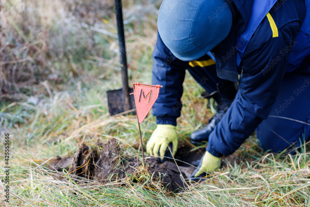 A man in a special suit works with a detector and found an explosive device. Dangerous work A man in a special suit works with a detector and found an explosive device. Dangerous work