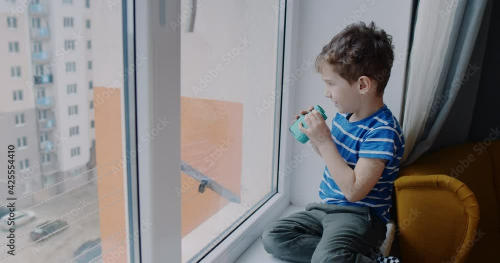 A small child, looking through binoculars outside the house window. A small child, looking through binoculars outside the house window.