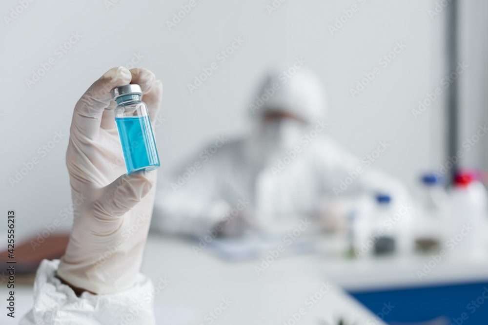 Obraz premium Jar with blue vaccine in hand of scientist in laboratory