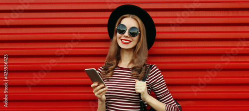 Portrait close up of smiling woman with smartphone on a red background
