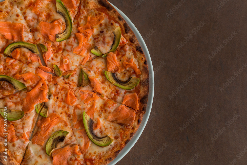 Pizza with salmon and avocado close-up