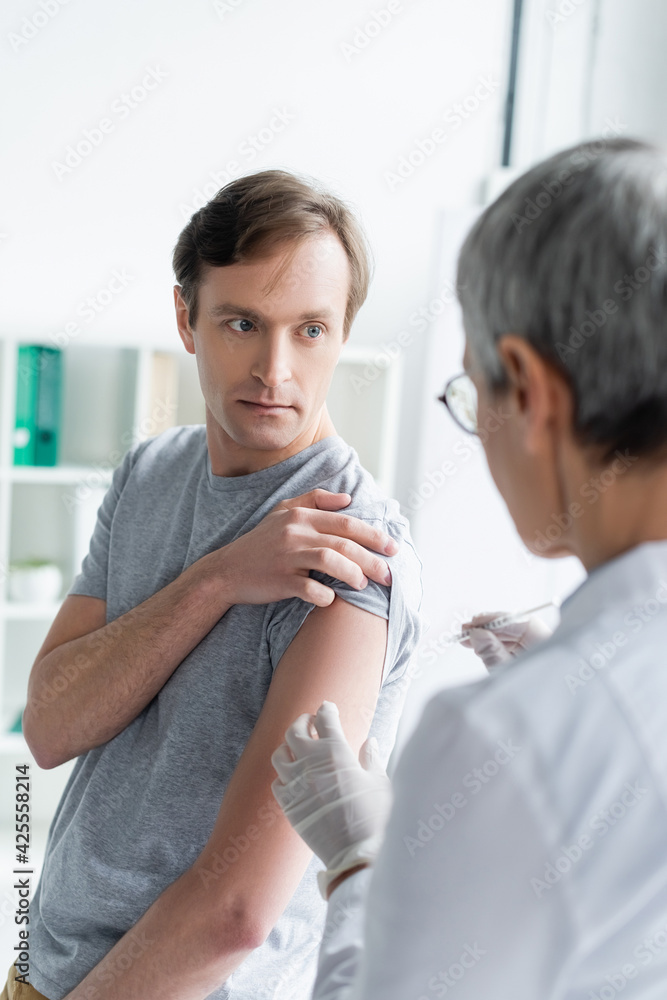 Patient looking at doctor with syringe during vaccination Patient looking at doctor with syringe during vaccination