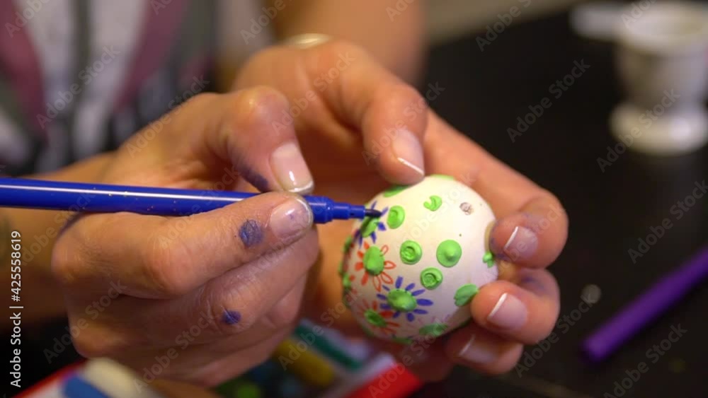 Easter egg painting and decorating activity concept: Human hands holding colorful handmade Easter eggs. Preparation for the holidays. Stationary objects on the table. Creative indoor decoration. Easter egg painting and decorating activity concept: Human hands holding colorful handmade Easter eggs. Preparation for the holidays. Stationary objects on the table. Creative indoor decoration.