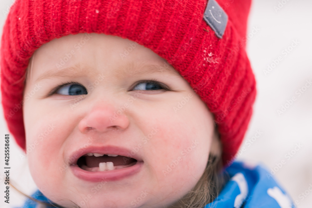 Cute toddler girl with blue eyes and red hat. Warmly dressed. Winter background. Cute toddler girl with blue eyes and red hat. Warmly dressed. Winter background.