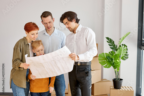 Young family talking with real estate agent while analzying housing plans during meeting photo