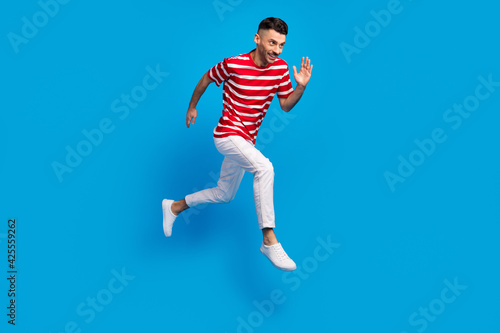 Full size profile side photo of happy man hurry sale jump run isolated on pastel blue color background