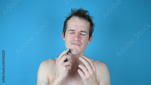 Portrait of a sad disgruntled man on blue background. Skin irritation after shaving on mans skin
