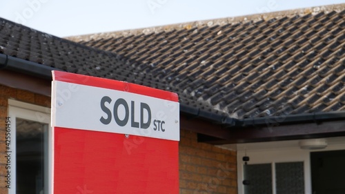 Red sold sign in front of house, sold property
