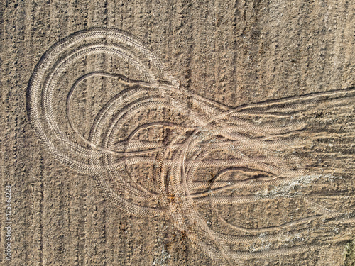 Top view of the tracks from the wheels of tractors after the harvest. An abstract pattern created by agricultural machinery on the ground. A circular pattern left behind by a vehicle.