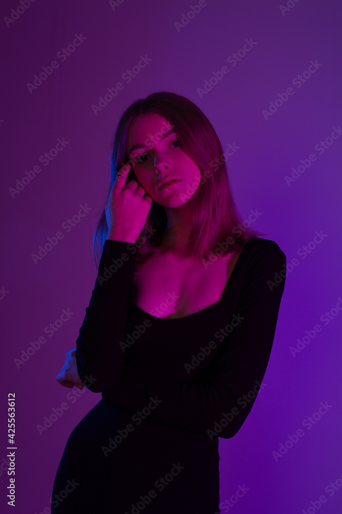Girl portrait in neon light. Young slim woman model in black dress Girl portrait in neon light. Young slim woman model in black dress