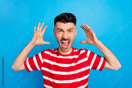 Photo of mad furious young unhappy man raise hands scream conflict isolated on pastel blue color background