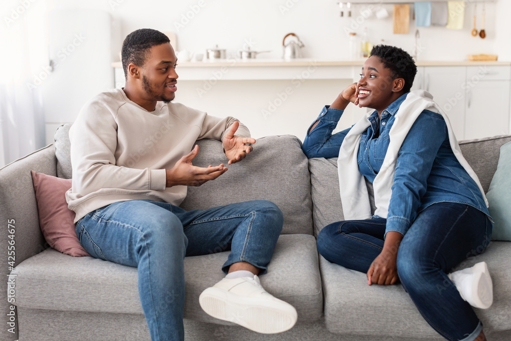 Black couple talking and spending time together sitting on couch Black couple talking and spending time together sitting on couch