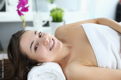 Smiling woman lies on table in spa center
