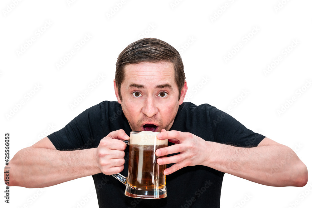A man in a black T-shirt drinks beer while holding a glass with both hands. Isolated white background. A man in a black T-shirt drinks beer while holding a glass with both hands. Isolated white background.