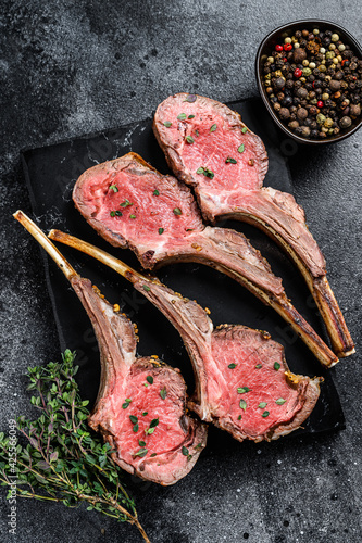 Roast lamb rib chop meat steaks on a marble board. Black background. Top view
